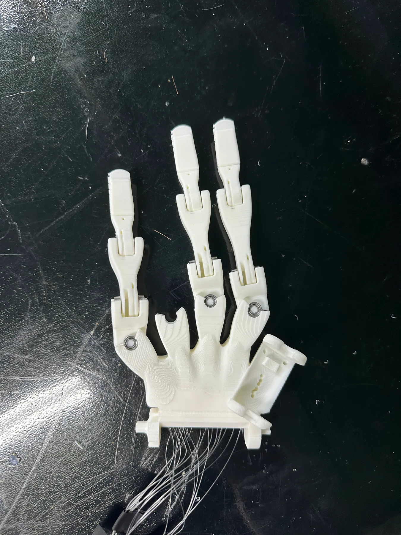 Close-up of a white tendon-driven robotic hand on a workbench