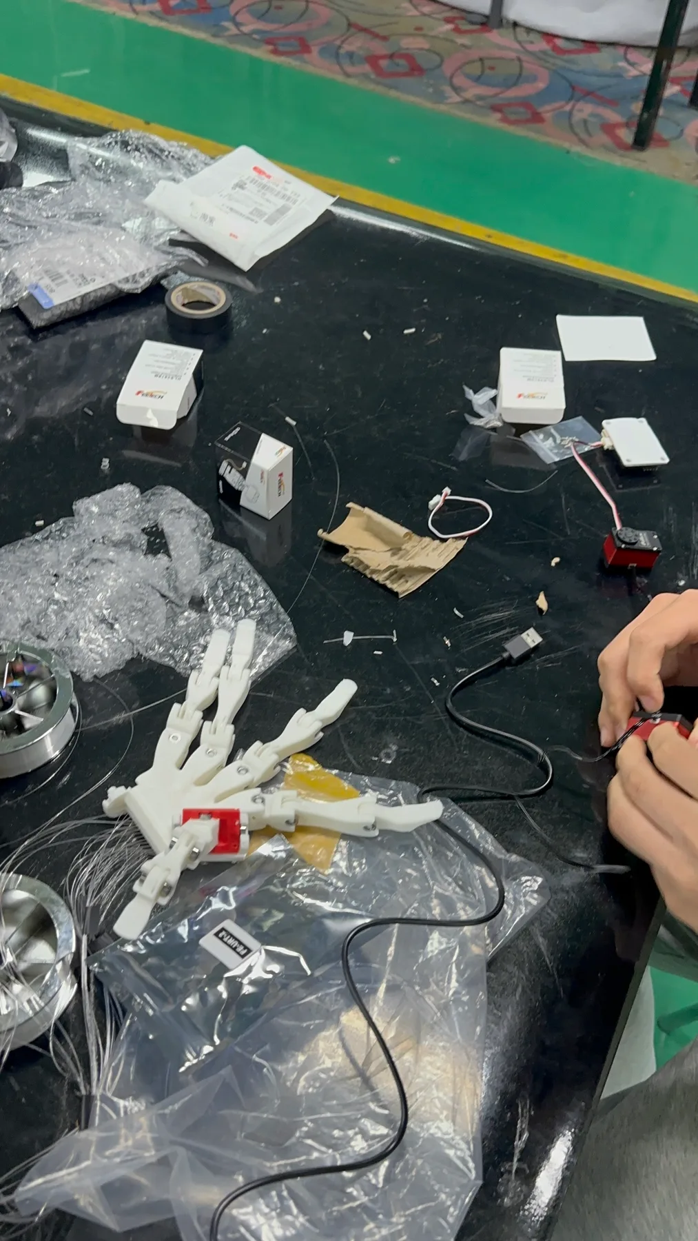 Robotic hand, servos, and wiring on the workbench.