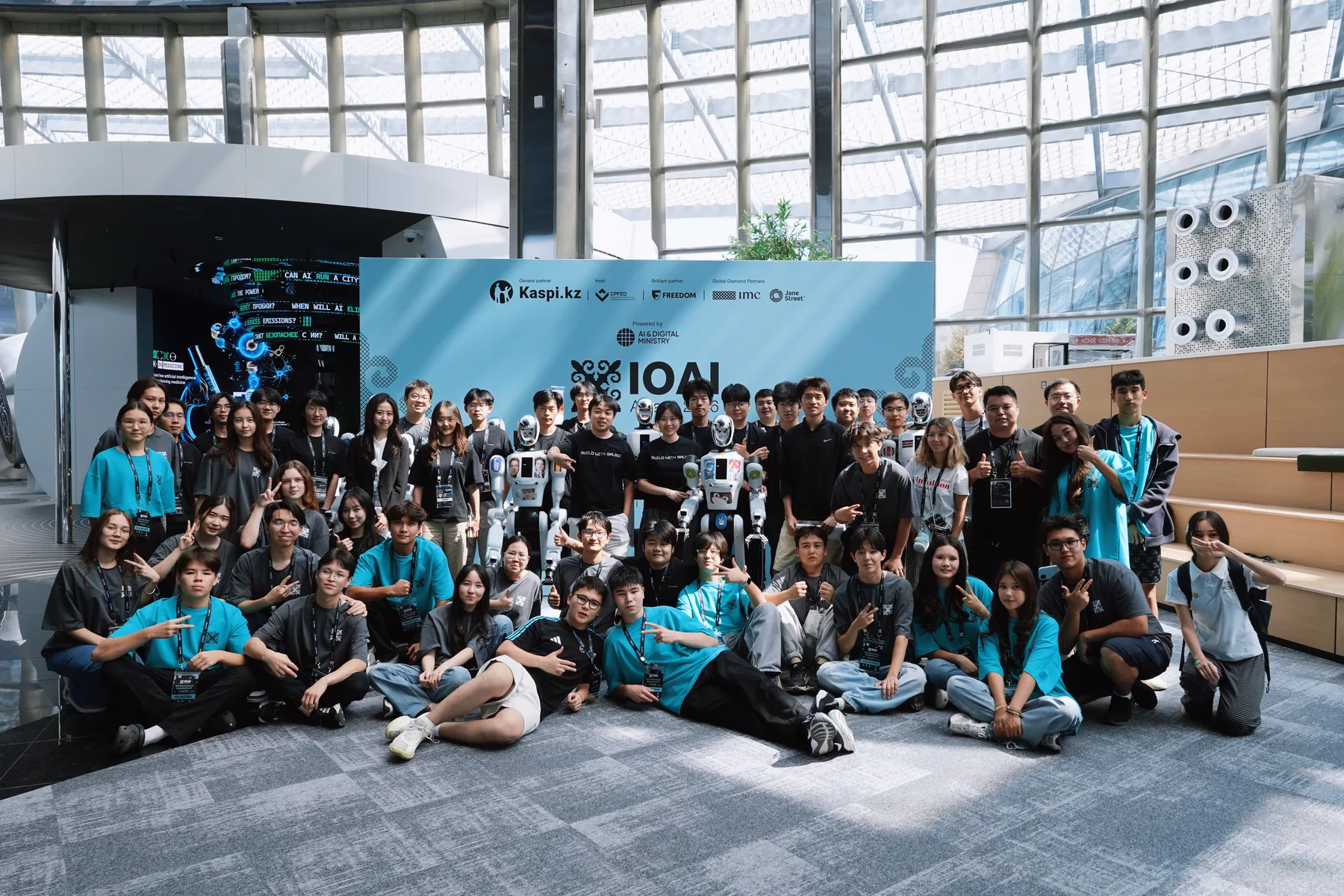 Group photo with robots in front of the IOAI event backdrop